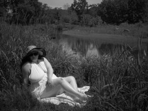Serene black and white image of someone reclining in a meadow wearing summer clothing.