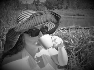 Vintage-style photograph showing figure in sunhat relaxing outdoors in natural setting.
