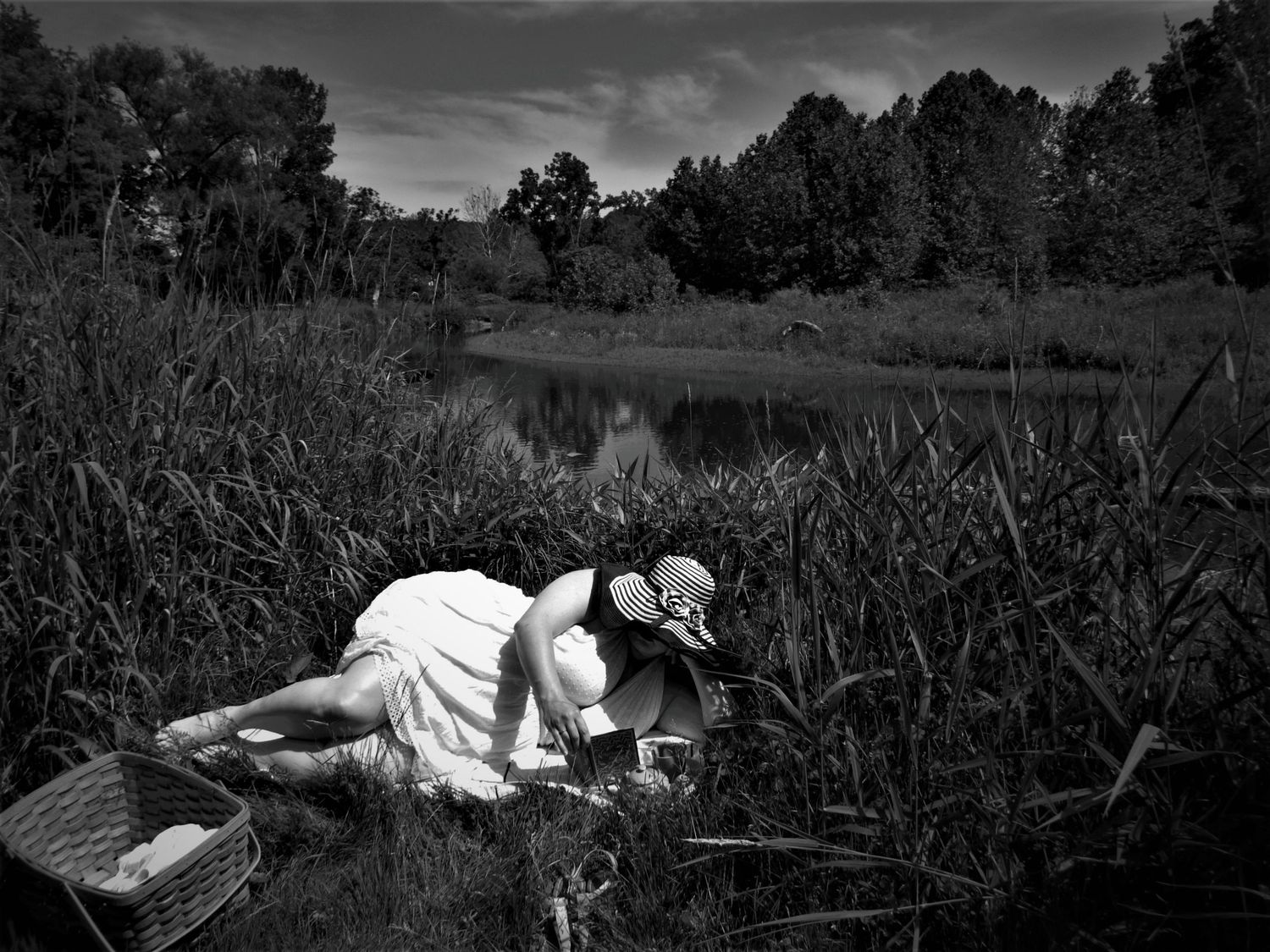 Scenic black and white image of natural setting with person in white dress by waterside.