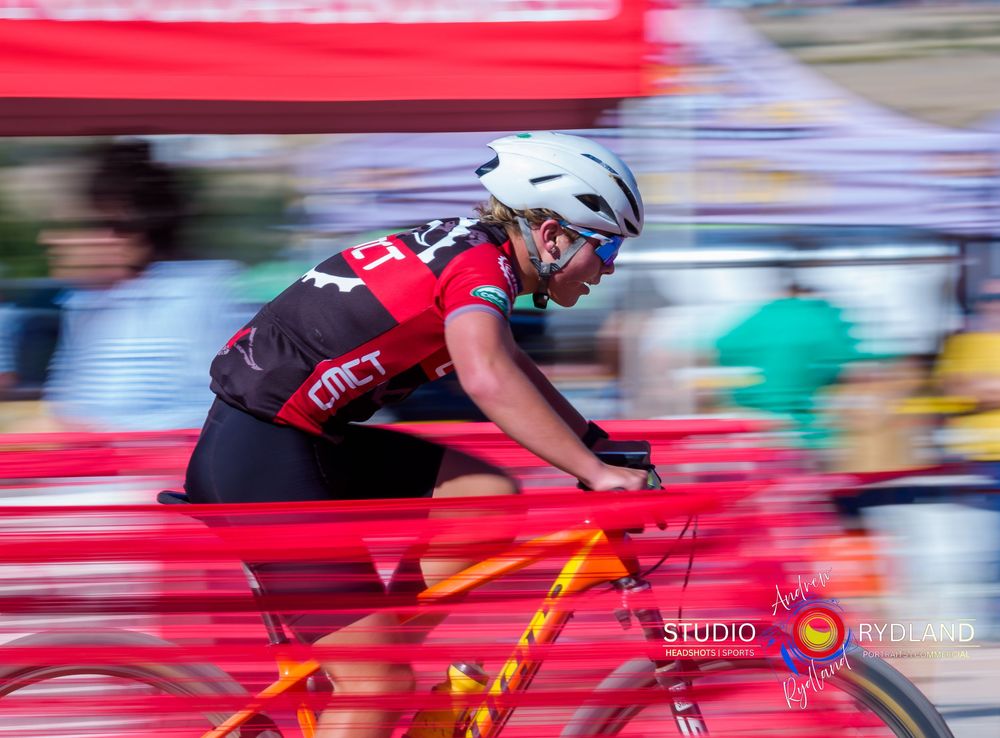 Motion blur captures cyclist in red jersey racing past on bright red bicycle during competitive event.
