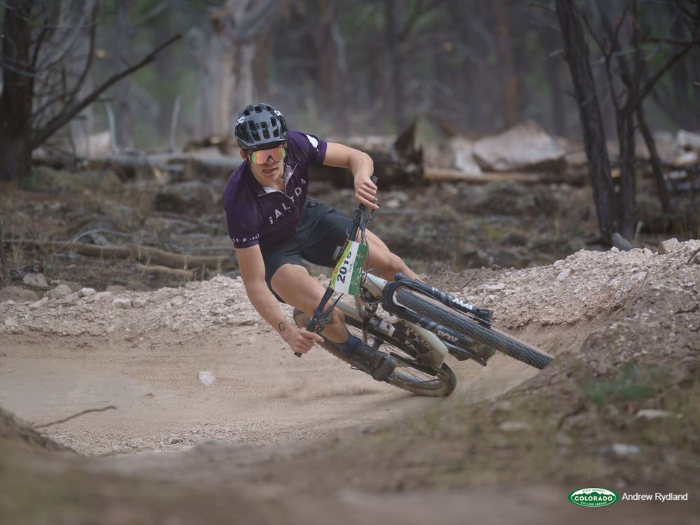 Mountain biker leans into dusty trail turn during downhill race.