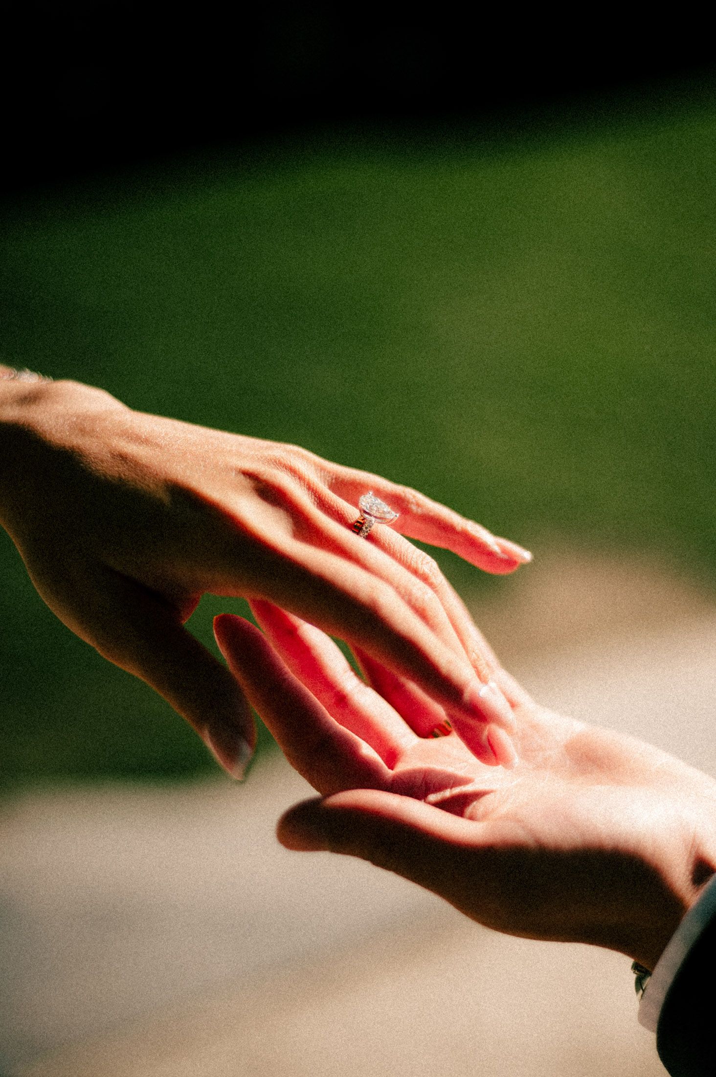 Close-up of hands exchanging wedding rings with red nail polish.