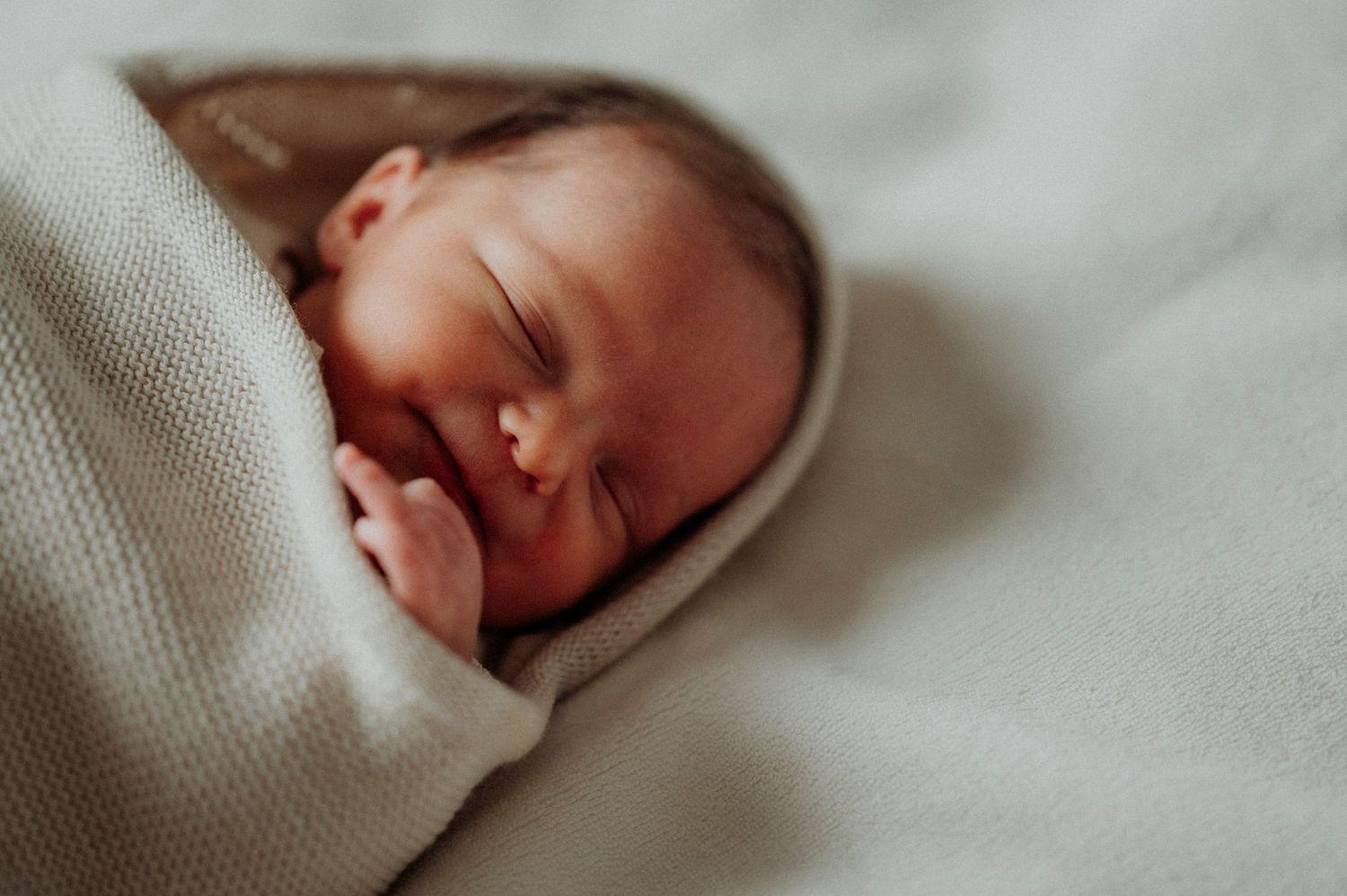 Een foto van een pasgeboren baby in de armen van mama in Leuven.