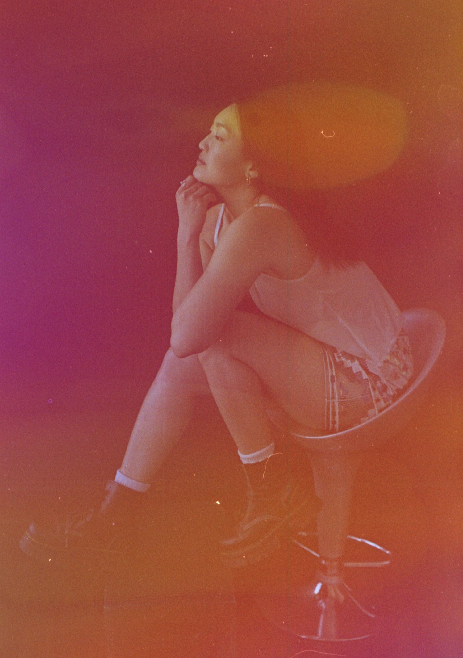 Stylish pose against vibrant orange and pink gradient background.
