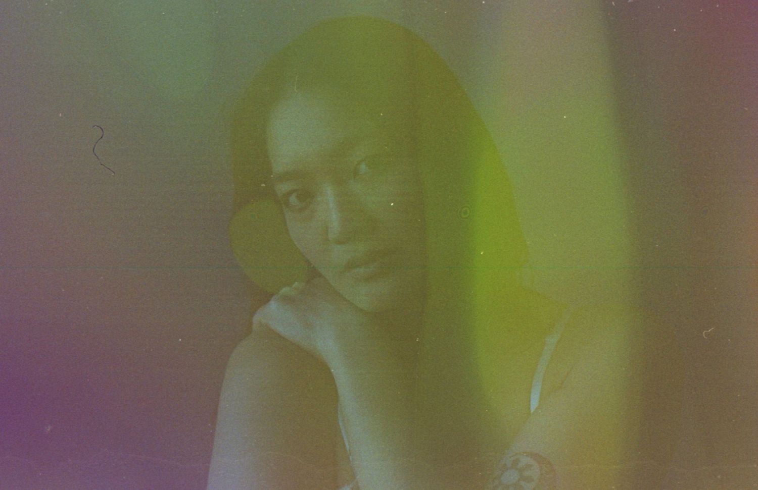 Artistic portrait with soft focus and dreamy purple and yellow gradient lighting.