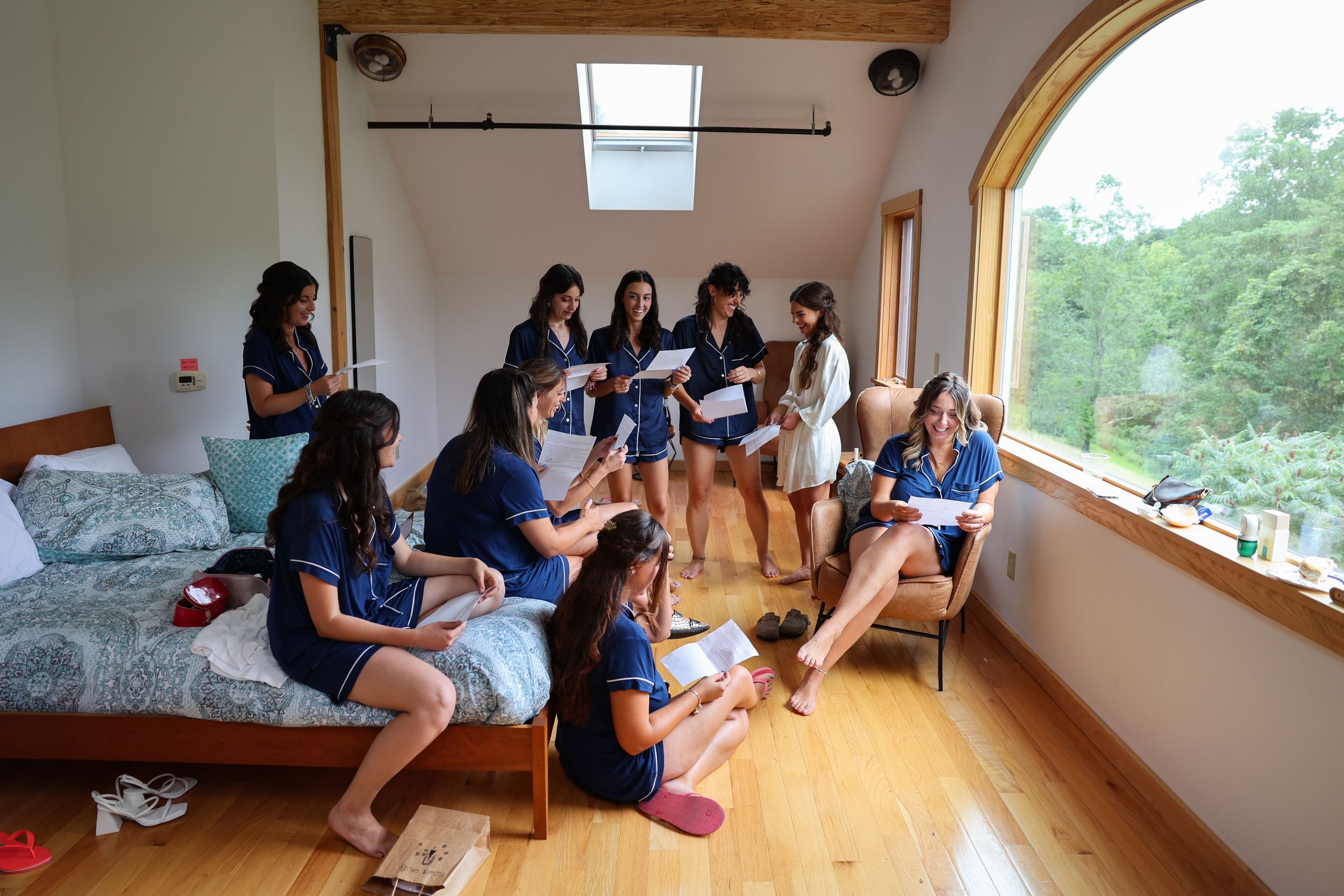 Group of friends relaxing in a sunlit room with large windows overlooking green scenery.