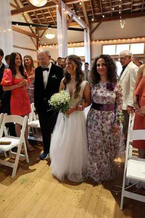 Wedding party members and guests gather in a rustic barn venue decorated with string lights.