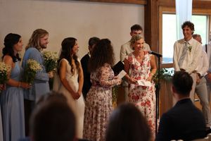 Wedding party guests mingling and chatting in formal attire at an indoor reception venue.