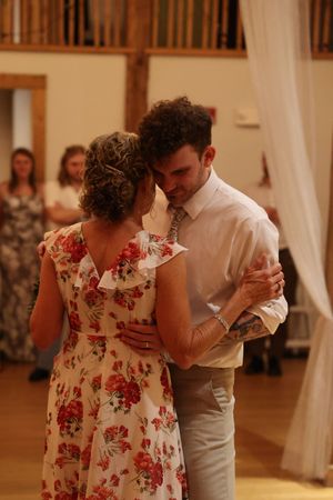 Dance sequence shows a mother-son dance with floral dress at an indoor wedding reception.