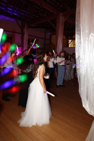 Wedding reception dance floor illuminated with colorful lights and white fabric draping.