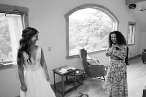 Two people share a joyful moment together in a bright room with an arched window, captured in black and white.