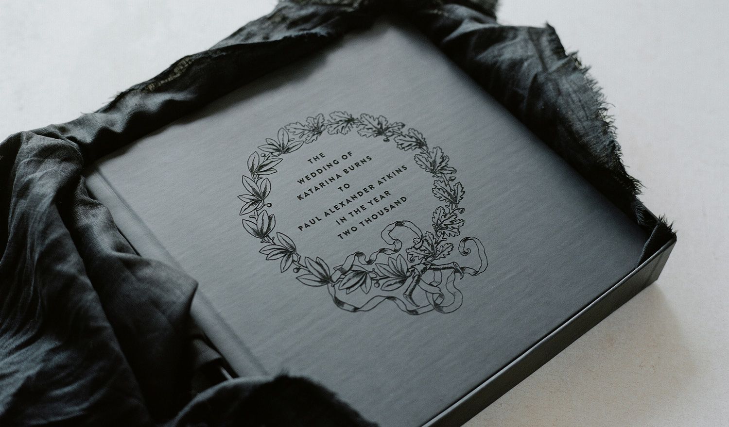 An antique black leather-bound book with an ornate floral design on the cover.