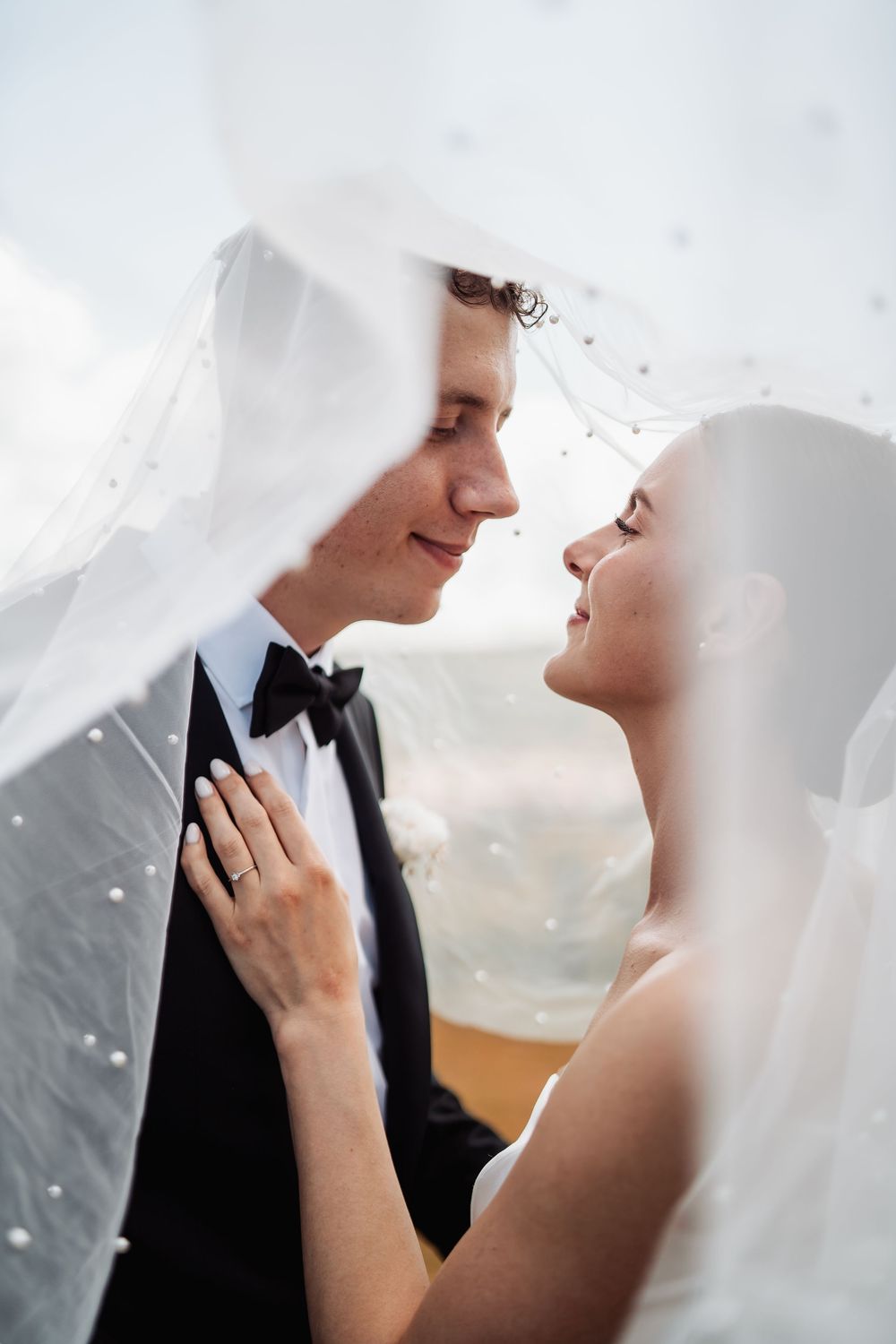 Romantic wedding photography series showing a bride and groom in tender moments behind flowing white veil.