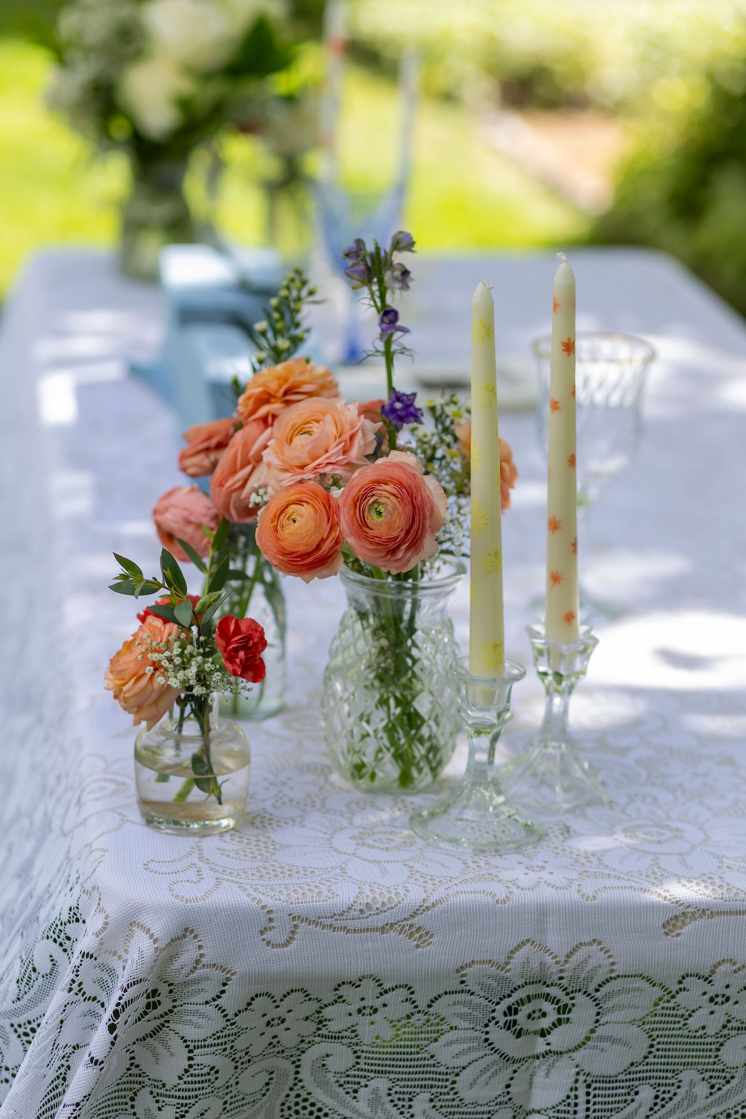 Sweetheart's table with white lace tablecloth. orange and pink flowers and candles.