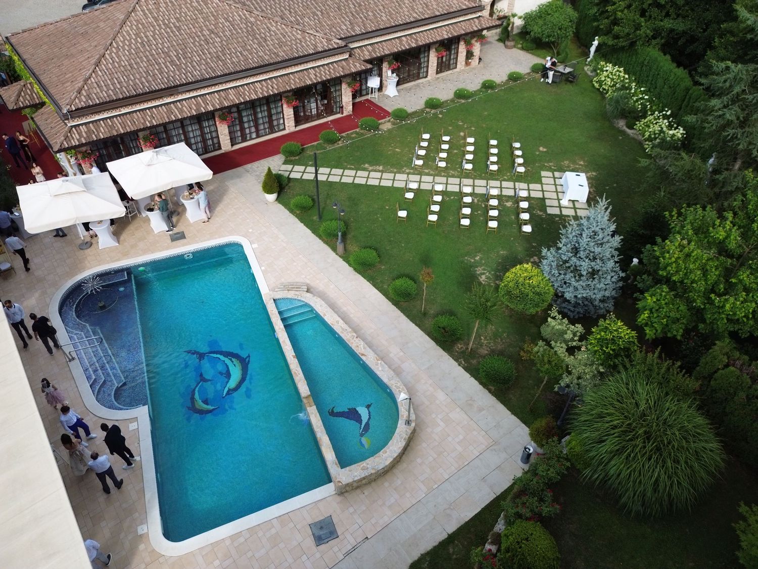 Aerial view of outdoor wedding ceremony setup with white chairs arranged in rows and a stone pathway leading to the altar area.