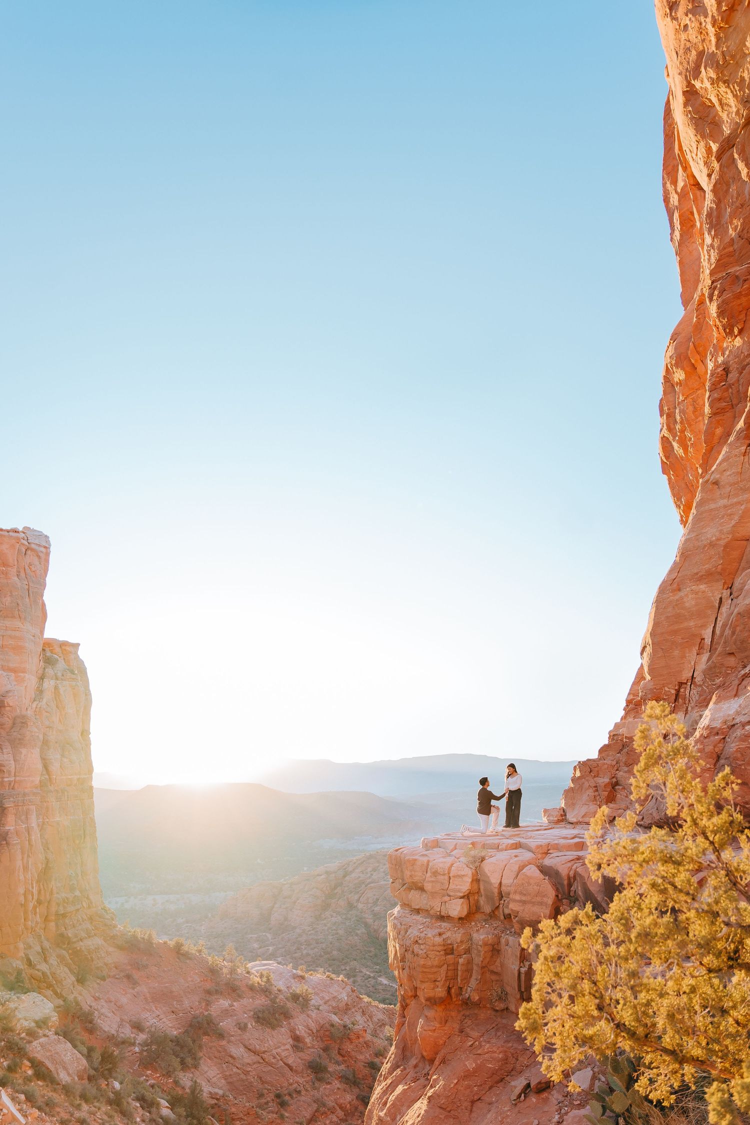 Scenic desert proposal moment framed by golden sunlight and towering red rock formations.