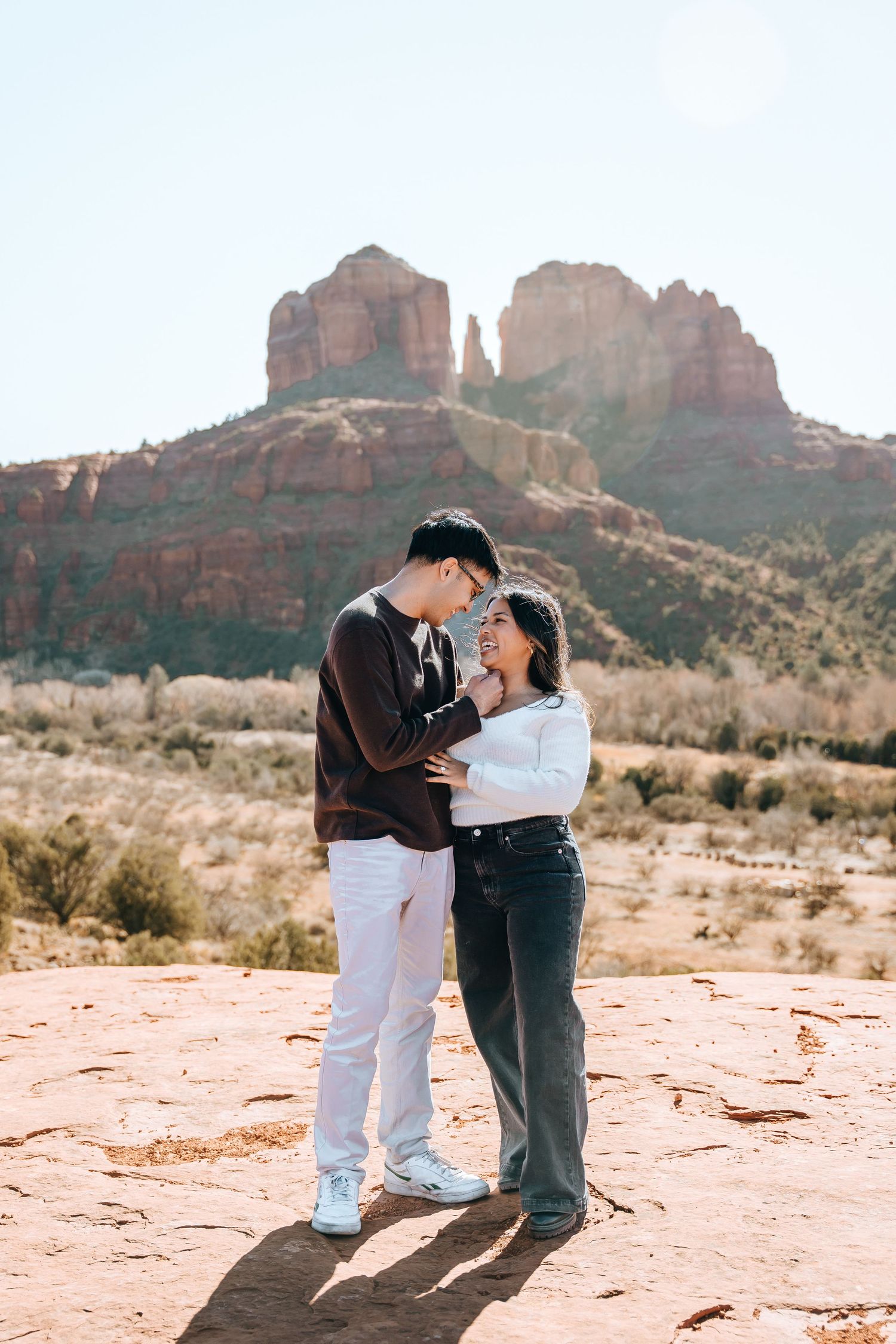 A tender embrace shared between two people on red desert rocks with mountain views.