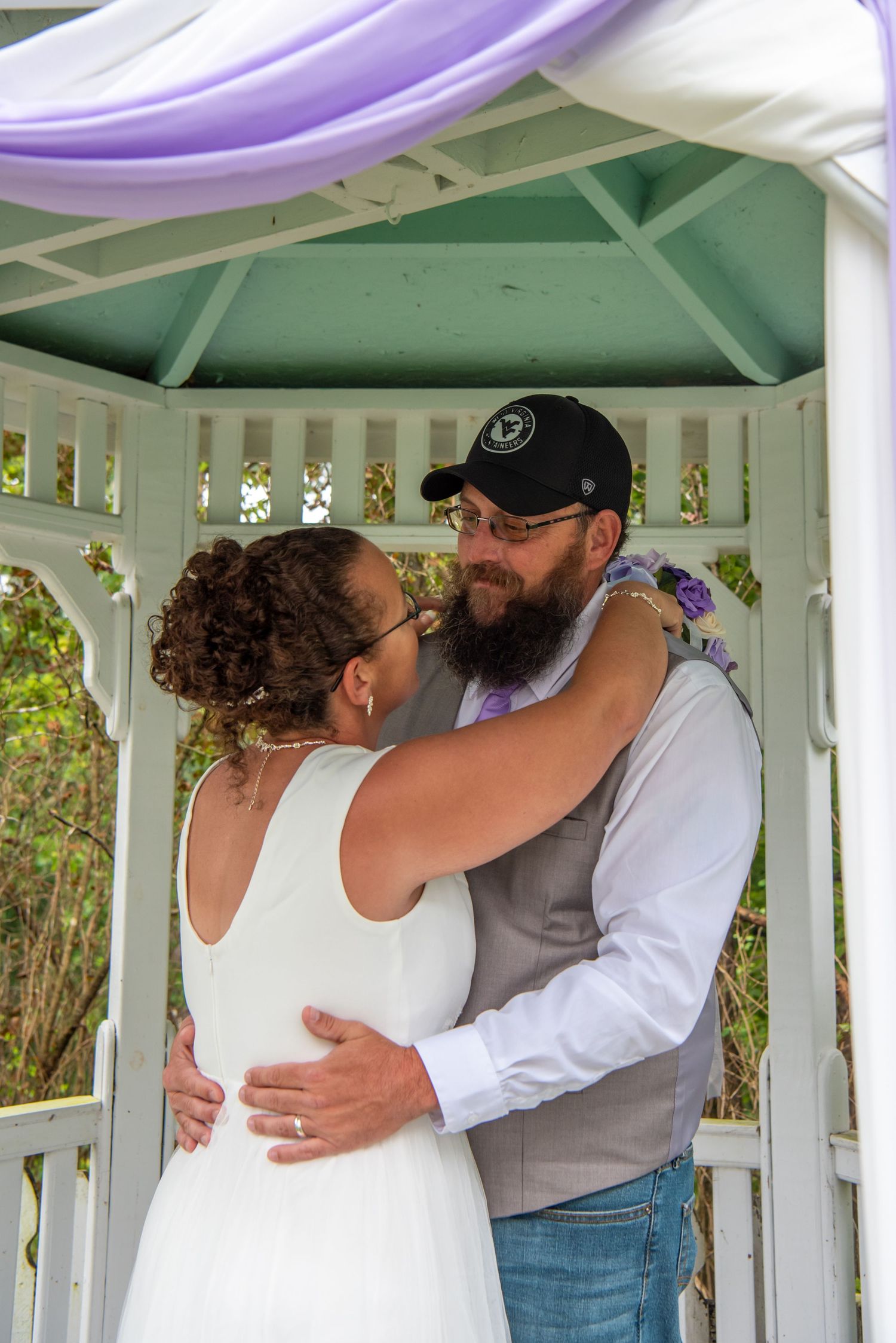 A romantic kiss sequence of a couple in a white gazebo on their wedding day.