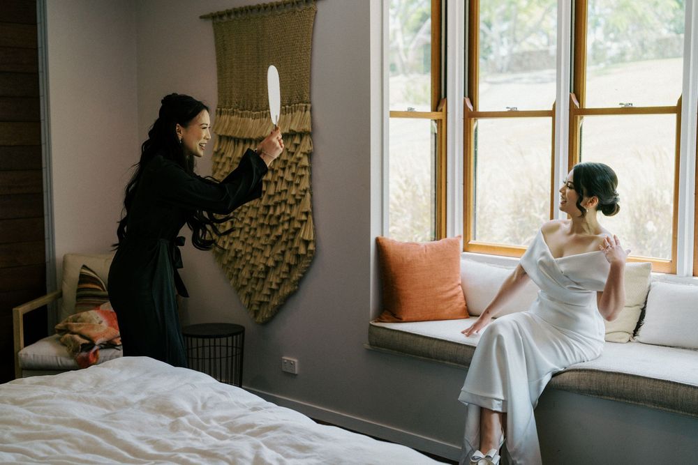 A bridal preparation scene in a sunlit room with photography and wedding preparations underway.