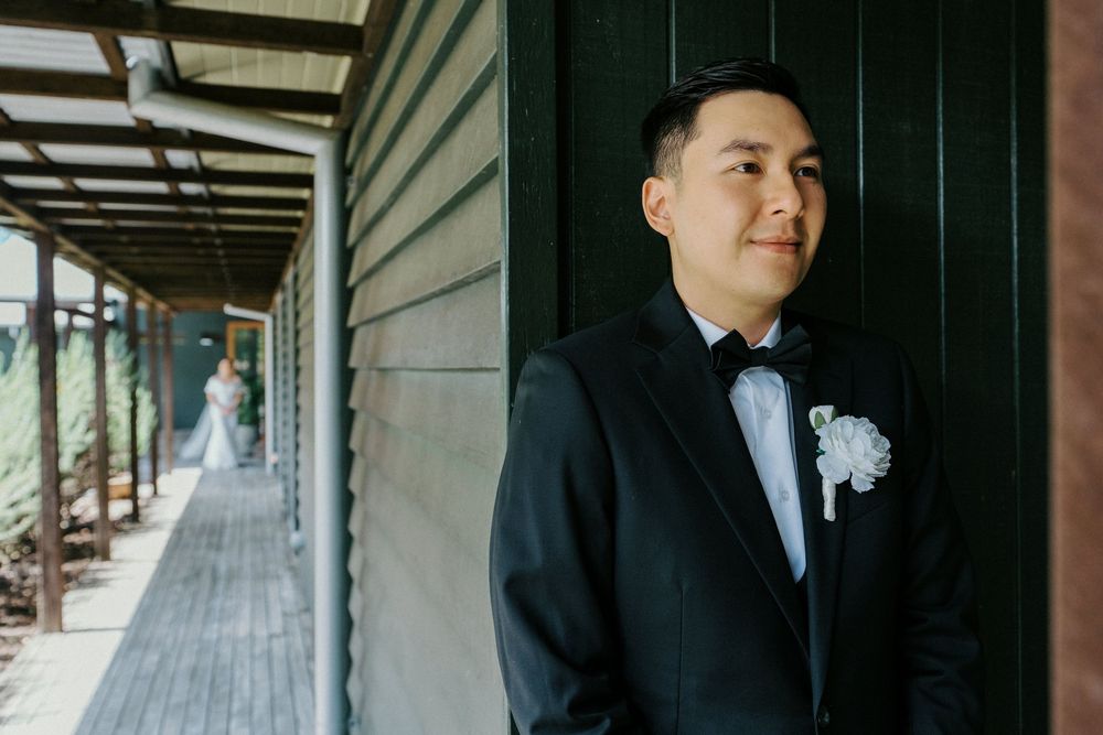 Wedding party poses along a covered wooden porch with dramatic lighting and architectural details.