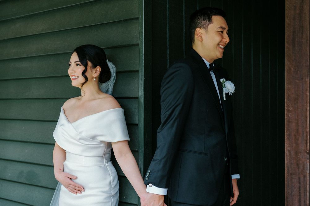 Wedding couple sharing a tender moment against a dark green wooden wall backdrop.