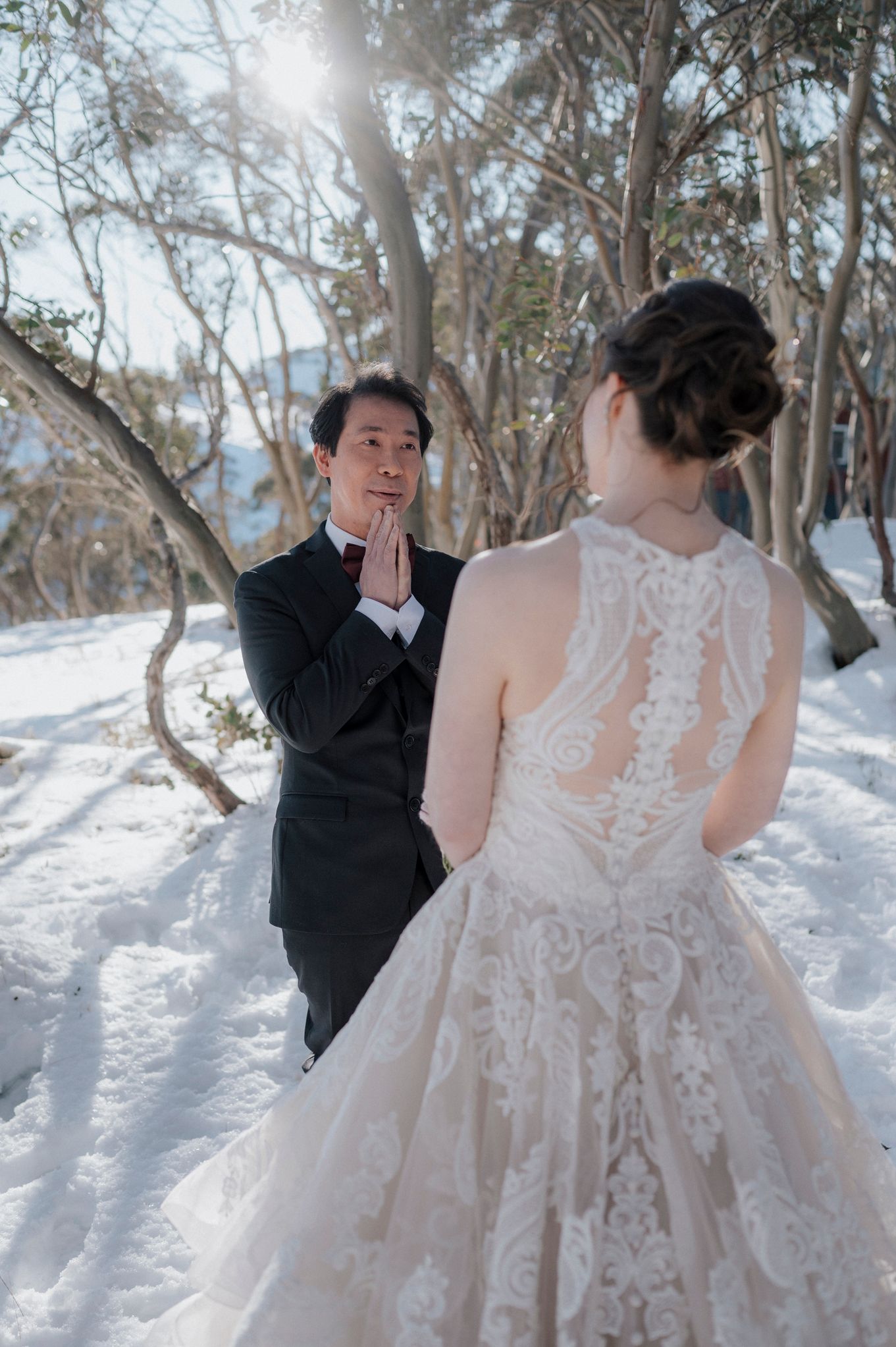 A winter wedding scene showing a couple in formal attire against a snowy forest backdrop with white trees.