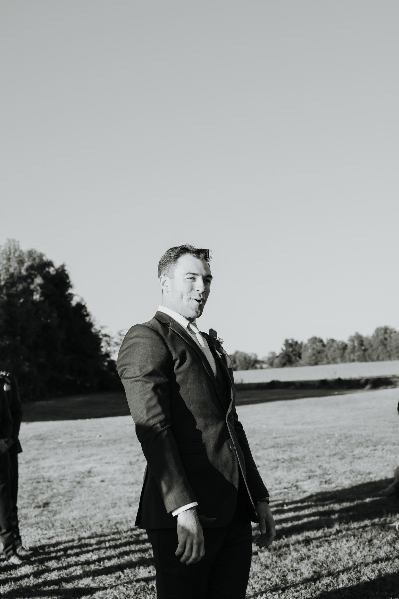 Black and white portraits in an open field with dramatic sky.