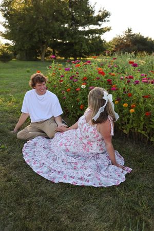 Couple relaxing on grass near a colorful garden of zinnias and wildflowers.