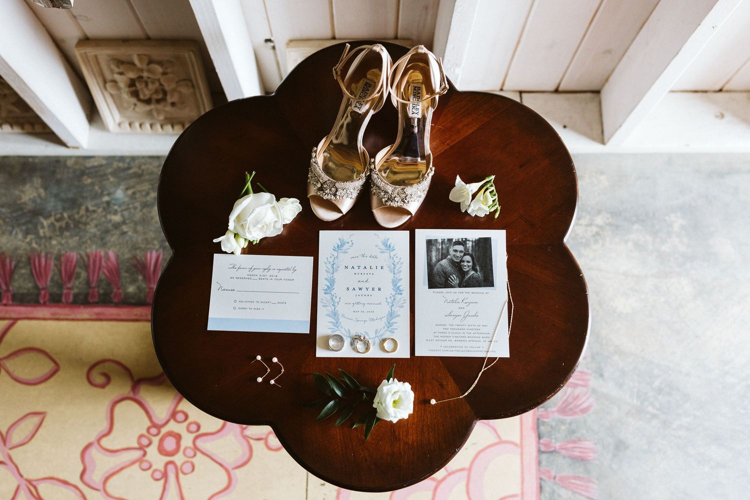 Wedding reception details with place cards and decorative items arranged on dark wooden tables.