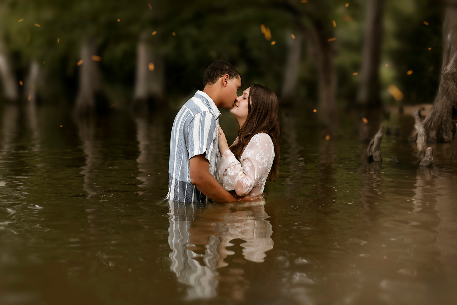 A couple shares an intimate kiss during their wedding photoshoot in a rustic wooded setting.