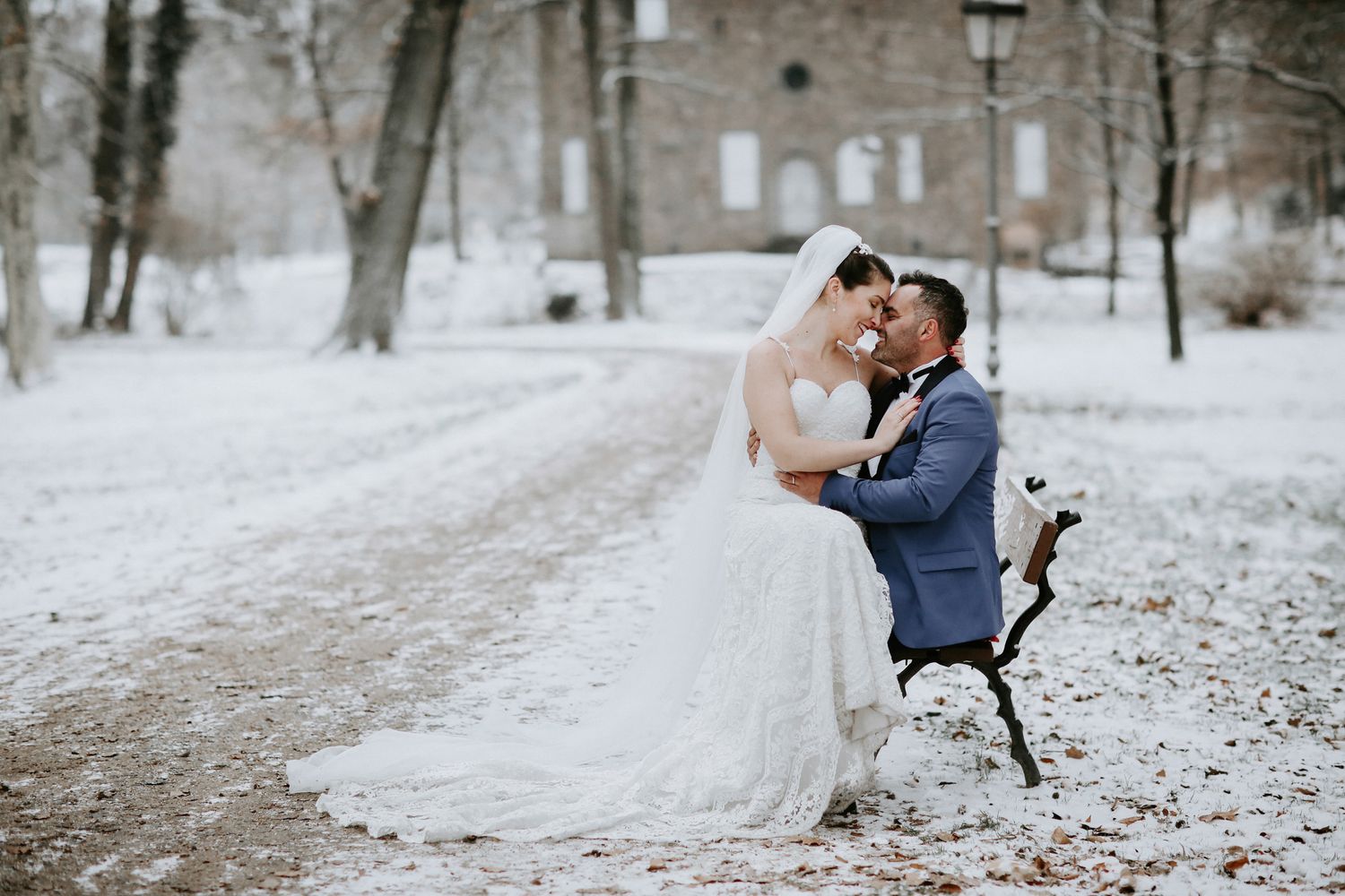A romantic winter wedding couple embraces in a snowy forest setting creating an ethereal scene.