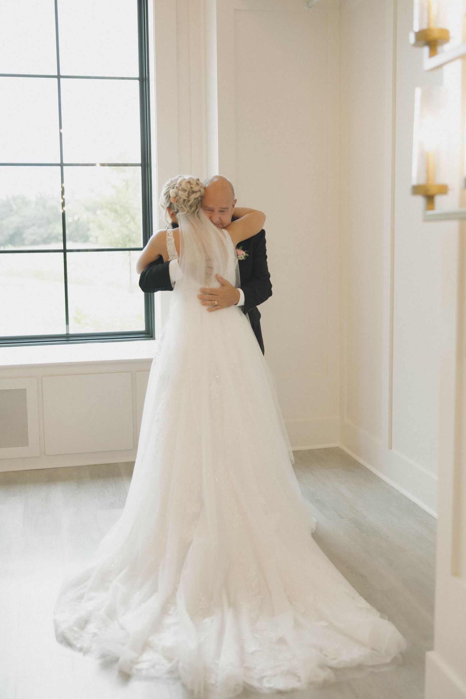 Multiple views of an elegant white lace wedding gown with flowing train showcased in a bright modern room with windows.