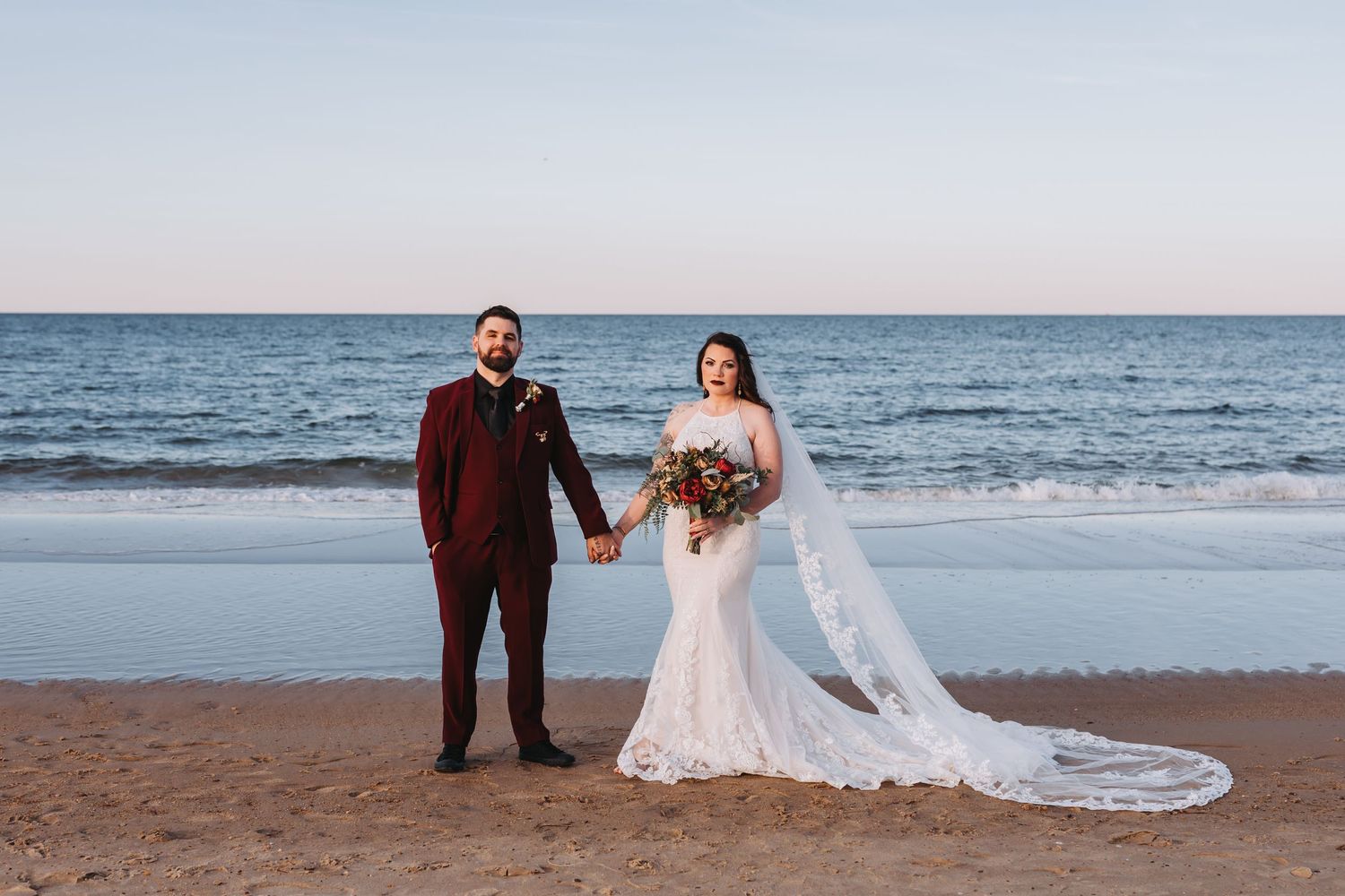 A couple embraces under an umbrella in the rain during what appears to be a wedding photo session.