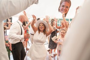Wedding guests celebrate and dance joyfully at a reception with people wearing white and festive attire.