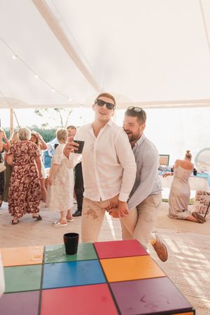 People dancing and jumping over vibrant colored cube blocks at a lively party under a tent.