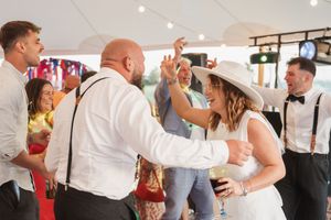 Happy wedding reception moment of dancing and celebration with people in formal attire.