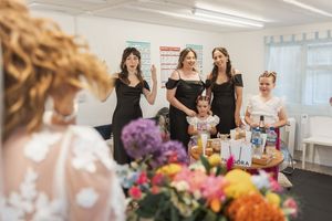 Group gathers in bright indoor space with floral arrangements and party decorations.