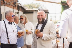 Guests enjoying drinks at an outdoor reception with sunglasses and casual summer attire.
