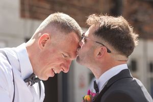 Emotional moment shared between two people outdoors in formal attire.