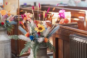 Rustic wooden church pews decorated with vibrant sunflowers and wildflower arrangements.