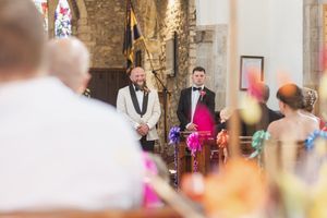 Traditional church wedding ceremony with guests seated in wooden pews and stone architecture.