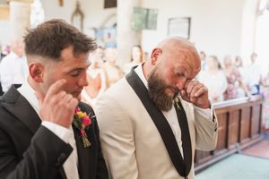 An emotional moment captured during a wedding ceremony in a traditional church setting.