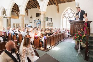 Wide angle view of a church wedding ceremony with guests seated in historic architectural setting.