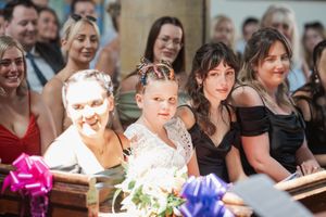 Wedding guests seated in rows share laughter and smiles during an indoor ceremony.