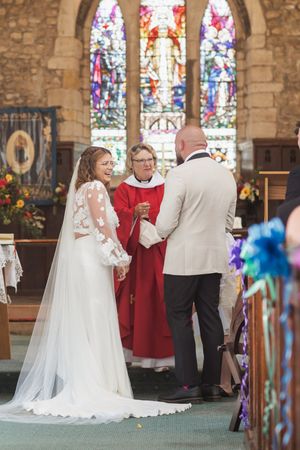 Wedding ceremony taking place in front of stained glass windows in historic church setting.