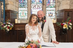 Beautiful church interior with stained glass windows and floral arrangements during wedding ceremony.