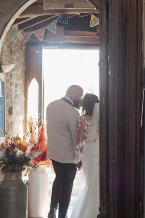Silhouetted figure arranges flowers in a vase near a sunlit window.