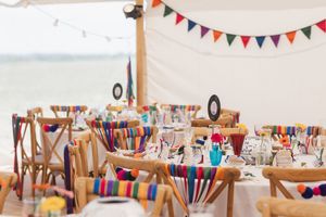Wedding reception tables decorated with colorful bunting and craft supplies for activities.