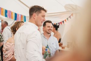 Festive indoor wedding reception with colorful banners and decorative bunting hanging overhead.