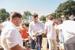 A lively outdoor summer gathering with guests in white shirts mingling on a sunny day.